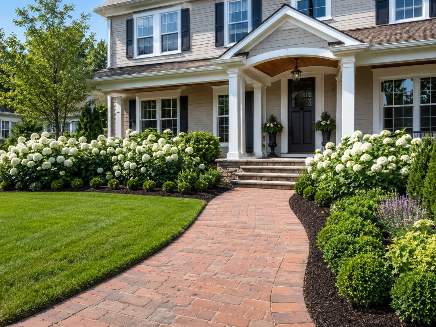 Front yard with brick walkway, fresh mulch, white flowering shrubs, and a welcoming front porch