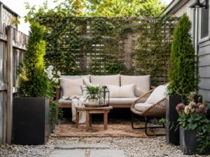 Small backyard seating nook with privacy trellis, outdoor bench, woven chair, planters and climbing vines